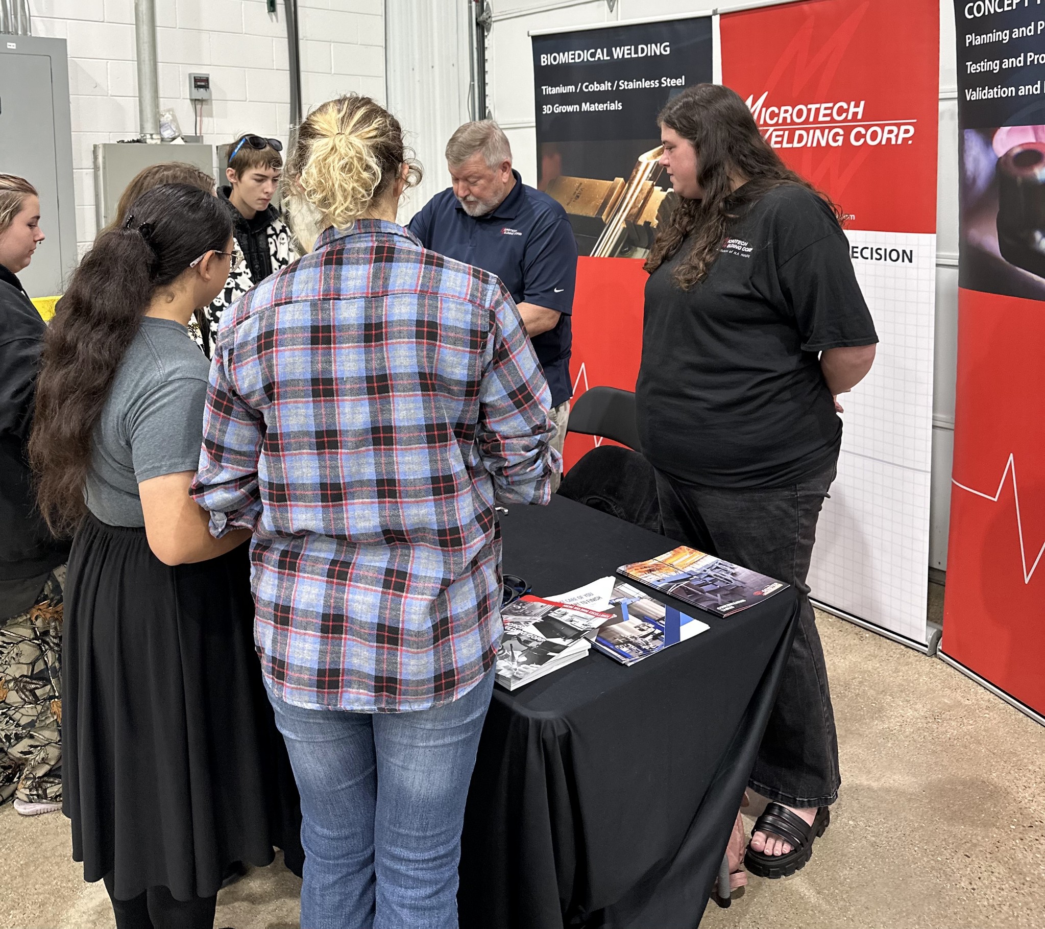 Two Microtech Employees at a Microtech booth with teenagers